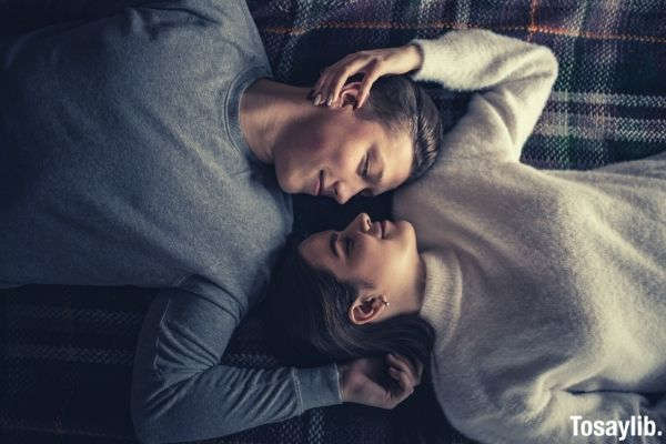 man and woman lying on the bed both wearing sweater long sleeves