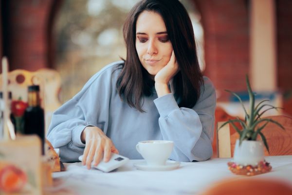woman bothered by her phone ringing while drinking coffee