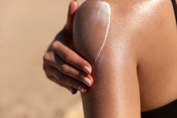 woman wearing sunscreen applying on skin