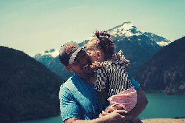 man-carrying-her-daughter-smiling-mountains-lake