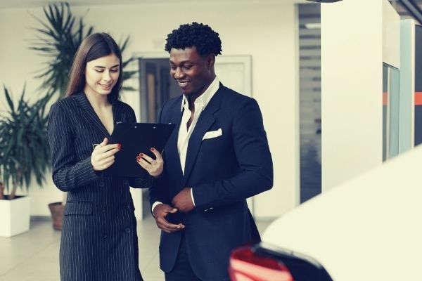 black man and white woman in formal attire talking man hand resume to friend