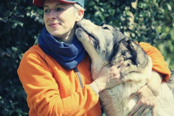 Lovely dog emotional support animal smelling its owner on orange and blue jacket while hugging