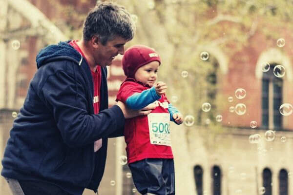 man-carrying-baby-playting-bubbles-jackets-outdoor