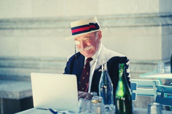 old-man-wearing-hat-and-monocle-using-laptop