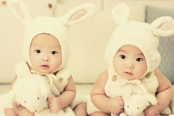 two-babies-wearing-white-headdress-white-holding-white-plush-toys﻿
