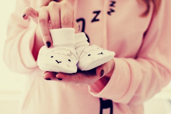 woman-holding-baby-s-pair-of-white-shoes