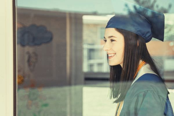 woman-in-blue-feature-academic-gown-smiling-looking-outside-the-window