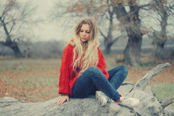 Feature-woman-in-red-sweater-sitting-on-cutted-tree