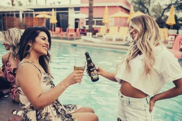 woman-on-pool-tossing-liquor-on-another-woman-wearing-hanging-white-shirt