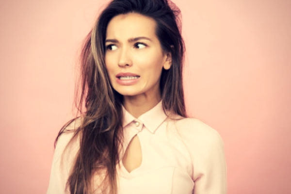 Feature-Woman-standing-against-a-pink-wall-looking-uncertain